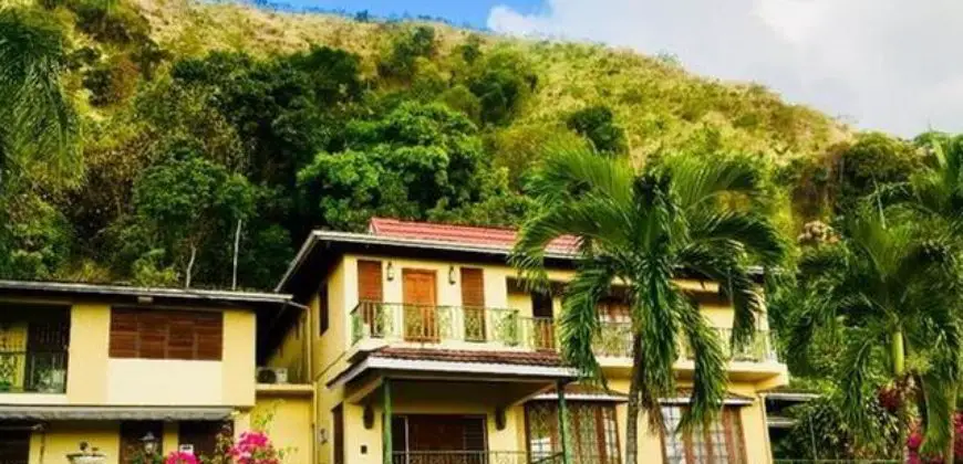 Charming older style home, surrounded by lush vegetation and nestled against a backdrop of hills